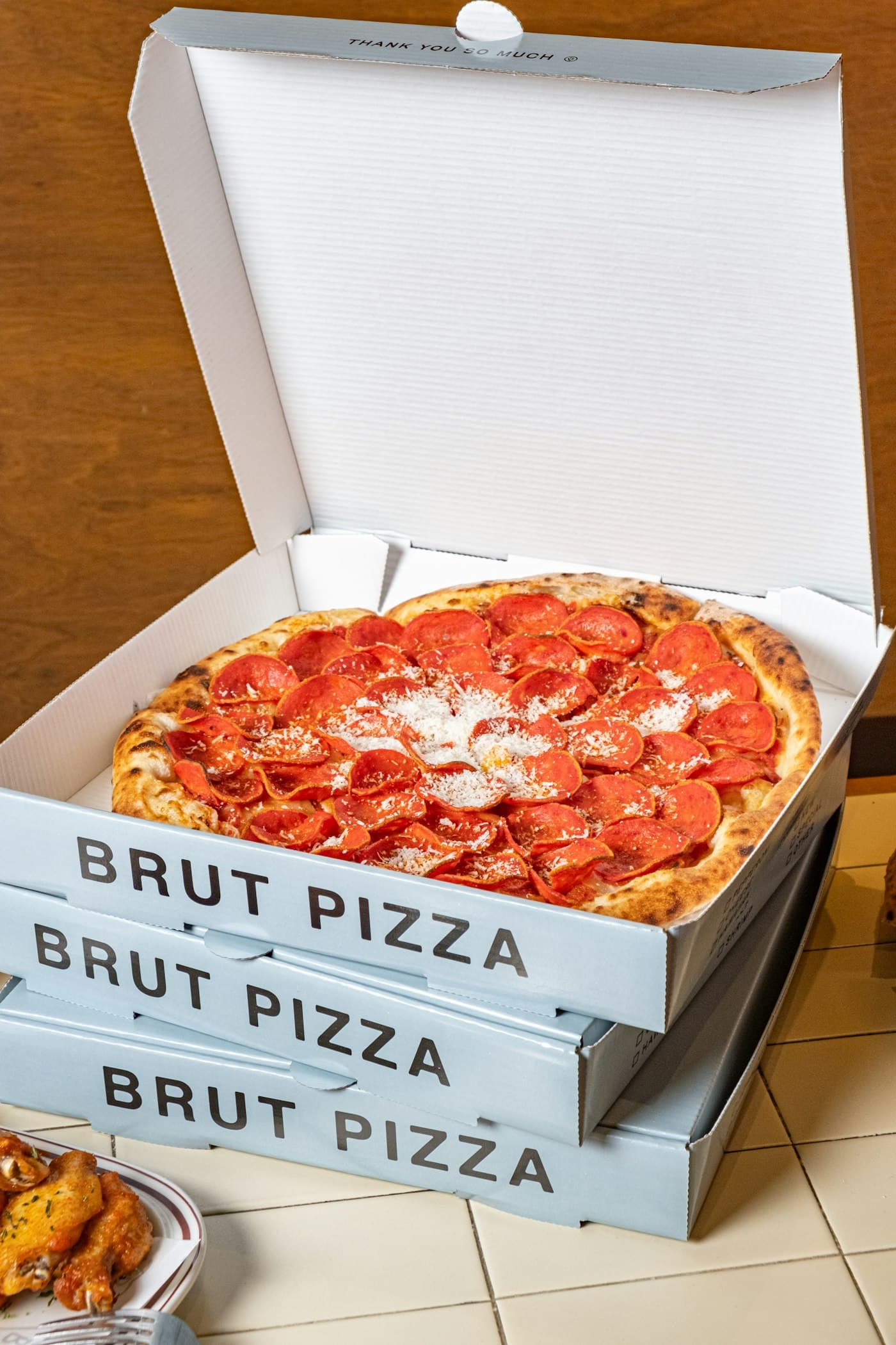 A pizza inside an open kraft corrugated pizza box on a table