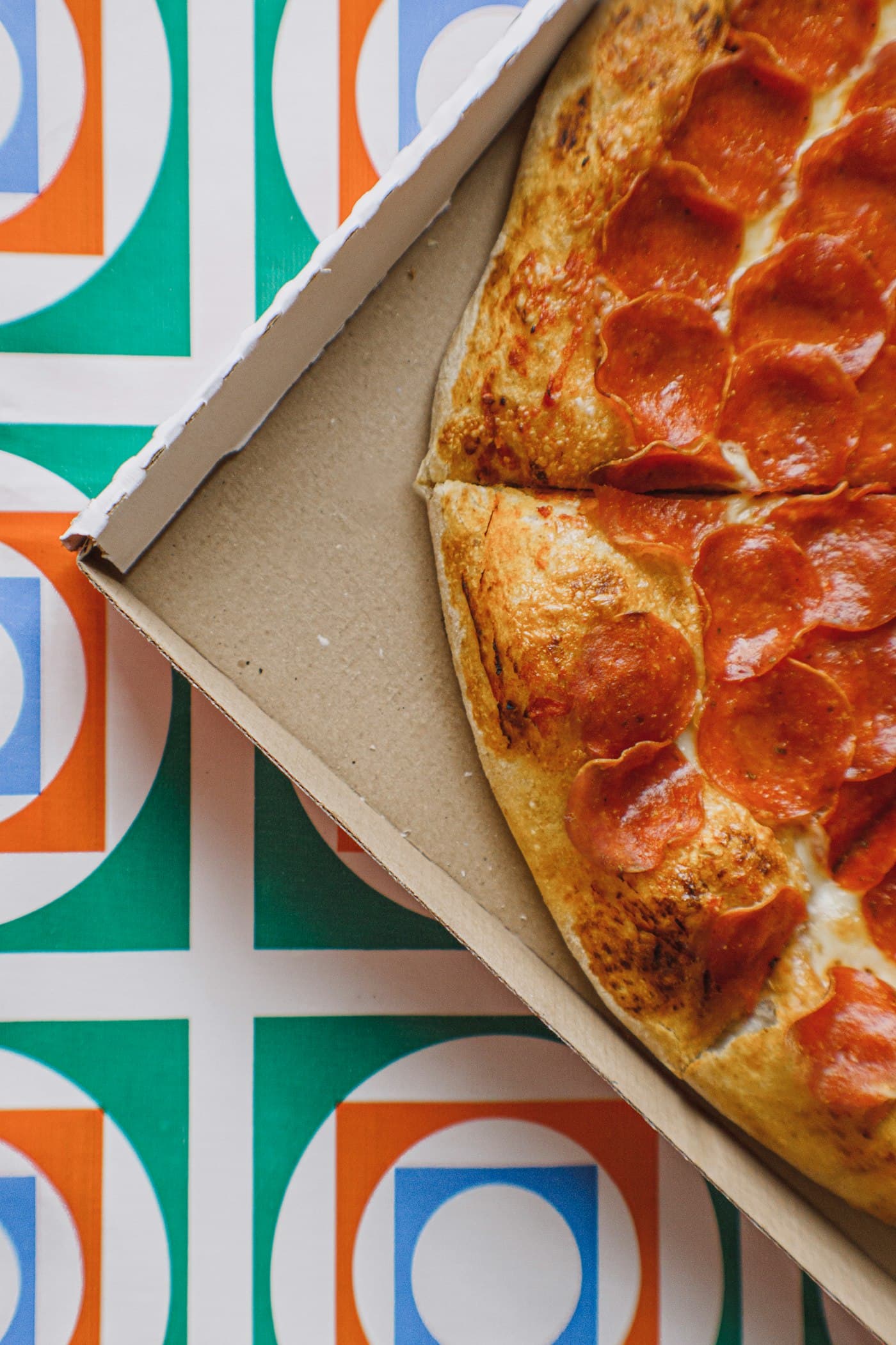 A pizza on a brown printed corrugated pizza box